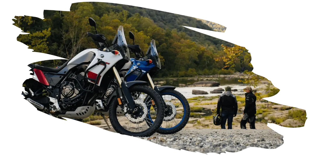 Two yamaha motorcycles parked while their drivers look at the river